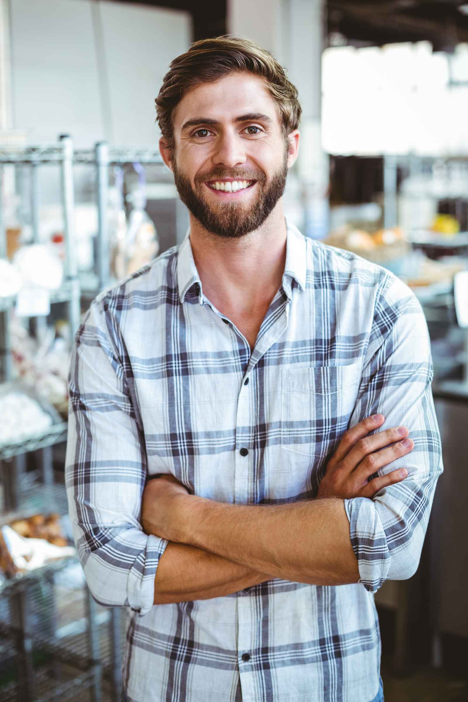 MINselfassured-waiter-smiling-in-front-of-his-bakery-PT2YTUK